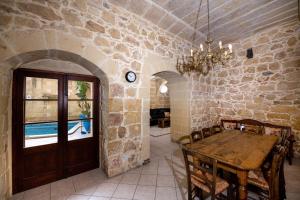 uma sala de jantar com uma mesa e uma parede de pedra em 4 Bedroom Farmhouse with Large Private Pool em Xewkija