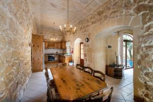a dining room with a wooden table and a stone wall at 4 Bedroom Farmhouse with Large Private Pool in Xewkija +21 photos