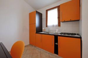 uma cozinha laranja com um lavatório e um fogão em casa vacanza mika em SantʼAnna Arresi