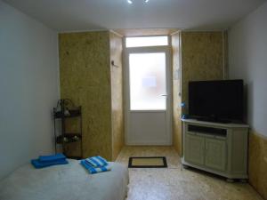 1 dormitorio con 1 cama, TV y ventana en Meublé Bulgarana - 4 pers en Bourg-Argental