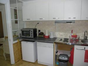 a kitchen with white cabinets and a microwave at Meublé Bulgarana - 4 pers in Bourg-Argental