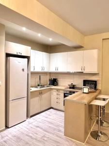  La cuisine est équipée de placards blancs et d'un réfrigérateur. dans l'établissement Dafni City Apartment 2, à Athènes