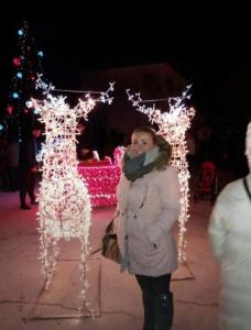 een vrouw die voor een kerstlichtsculptuur staat bij Villa Colonia Vir in Vir