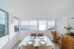 a dining room with a table and chairs and windows at Magnifique Maison Bramer 14, Roses - WeHostYou in Roses