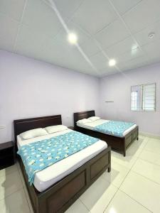 Habitación con 2 camas individuales y paredes blancas. en Thủy Quỳnh hotel, en Xóm Bên Ðông