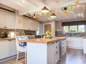 a kitchen with white cabinets and a wooden counter top at Bridge Farm in Uttoxeter
