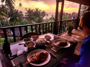 Lahiru Villa في غالي: شخص يجلس على طاولة مع أطباق من الطعام