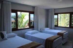 two beds in a room with two windows at Pousada Encantos de Arraial in Arraial d'Ajuda