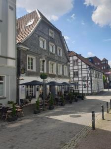 a building with tables and umbrellas on a street at Hotel Restaurant Meints4you im Bürgerhof in Recklinghausen