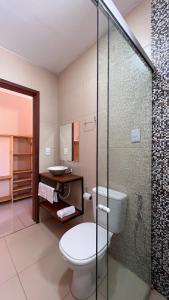 a bathroom with a toilet and a glass shower at POUSADA DONNA MARIA in São Miguel do Gostoso