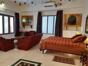 a bedroom with a bed and a chair and windows at Haveli Braj Bhushanjee Heritage Hotel in Būndi