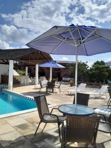 a table with an umbrella next to a pool at Casa 04 do Condomínio Privê Portal das Flores in Gravatá