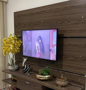 Elle comprend une télévision à écran plat installée au-dessus d'un mur en bois. dans l'établissement Apt temporada em Ponta Verde, à Maceió