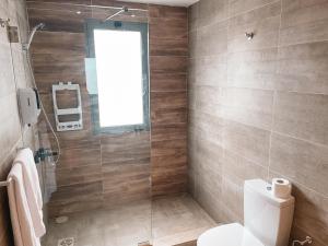 a bathroom with a toilet and a glass shower at Sky Suites in Accra