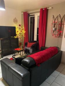 a living room with a black leather couch and red curtains at gite l'etoile de mer in Eu