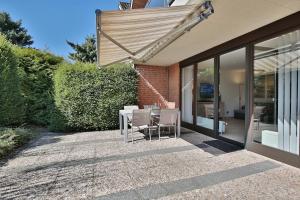 eine Terrasse mit einem Tisch und Stühlen unter Markise in der Unterkunft Doppelhaushälfte Am Knurrhahn Am Knurrhahn Appartement 2 in Haffkrug