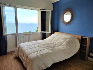 1 dormitorio con 1 cama con pared azul y espejo en Maison VUE MER avec jardin à 800m de la plage à TREBEURDEN REF-683 en Trébeurden