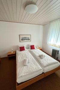 ein Schlafzimmer mit einem großen Bett mit weißer Bettwäsche und roten Kissen in der Unterkunft Apartment Chalet Holzwurm by Interhome in Grindelwald