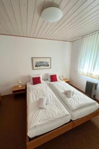 een slaapkamer met een groot bed met witte lakens en rode kussens bij Apartment Chalet Holzwurm-1 by Interhome in Grindelwald