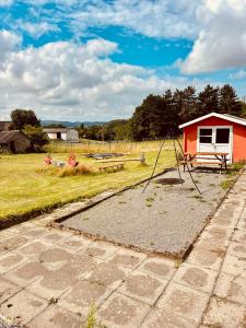 a playground in a field next to a red house at Extertal-Ferienpark - Premium Ferienhaus Sonnental - Sauna #50 in Extertal