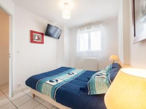 ein Schlafzimmer mit einem Bett mit einer blauen Bettdecke in der Unterkunft Apartment Les hauts de la corniche by Interhome in Mimizan-Plage