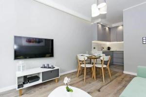 sala de estar blanca con mesa y cocina en Motlawa Riverview Apartment OIdtown, en Gdansk 4 fotos más