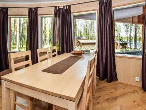 een eetkamer met een houten tafel en ramen bij Holiday Home Lepovalkeinen by Interhome in Pylkönmäki