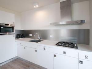 a white kitchen with white cabinets and a sink at Holiday Home Oesterdam Resort-1 in Tholen