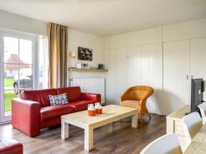 a living room with a red couch and a table at Holiday Home Bungalowpark It Wiid by Interhome in Eernewoude