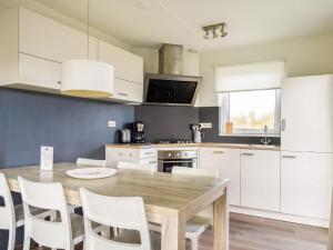a kitchen with a wooden table and white cabinets at Holiday Home Bungalowpark It Wiid by Interhome in Eernewoude