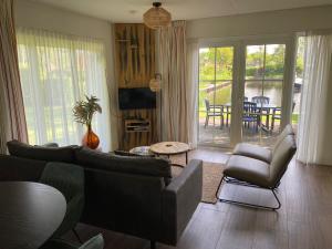 a living room with a couch and chairs and a patio at Holiday Home Bungalowpark It Wiid by Interhome in Eernewoude