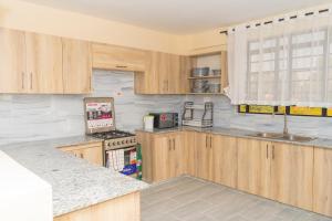 a kitchen with wooden cabinets and a stove top oven at Arabella Apartments in Bungoma
