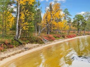 a dirt road next to a river with trees at Holiday Home Peurakumpu by Interhome in Ivalo