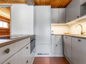 uma cozinha com armários brancos e um tecto de madeira em Holiday Home Villa virkeä by Interhome em Vierumäki