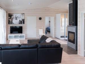 a living room with a black leather couch and a fireplace at Holiday Home Saana 4 by Interhome in Kilpisjärvi