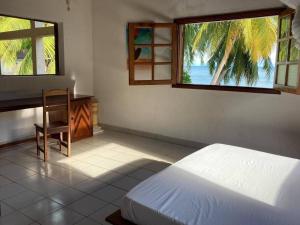 a bedroom with a bed and a desk and two windows at Villa Carla, vacances à la mer in Nosy Be