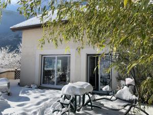 una casa con sedie ricoperte di neve nel cortile di La coccinelle a Noyarey