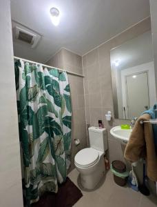 a bathroom with a toilet and a sink with a shower curtain at Tranquil in Manila