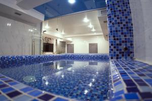 baño con bañera grande con azulejos azules en Shymkent Park Hotel, en Shymkent