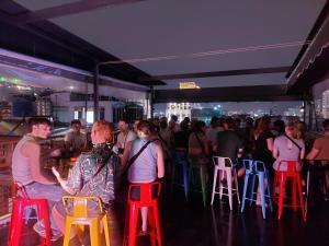 Une foule de personnes debout dans un bar avec des tabourets colorés dans l'établissement Saigon Rooftops Hostel, à Hô-Chi-Minh-Ville