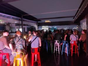 a crowd of people standing in a bar with red stools at Saigon Rooftops Hostel in Ho Chi Minh City