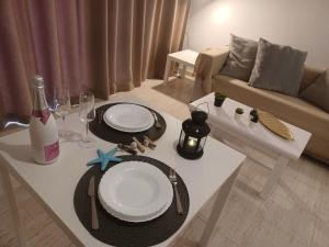 a white table with plates and wine glasses on it at Alisios Playa, pool view in Corralejo