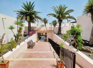 a walkway with palm trees and a building at Alisios Playa, pool view in Corralejo
