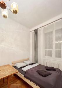 ein Schlafzimmer mit einem Bett und einem Tisch und einem Fenster in der Unterkunft Cozy studio in Cracow in Krakau