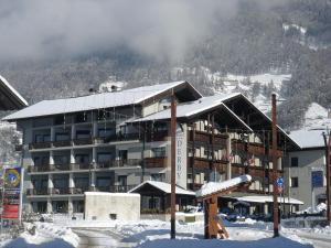 een groot gebouw in de sneeuw met een berg bij Hotel Derby in Bormio