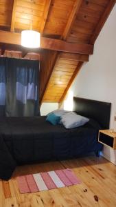 a black bed in a room with wooden ceilings at LOS ABEDULES in El Bolsón