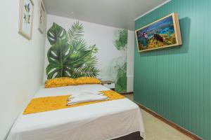 1 dormitorio con 1 cama con una pintura en la pared en NOMADA HOTEL GUATAPE en Guatapé