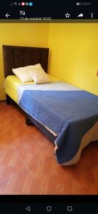 a bedroom with a bed with a yellow wall at Arriendo casa por dias en olmue in Olmué
