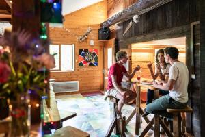 een groep mensen die aan een tafel in een kamer zitten bij Auberge de Jeunesse HI La Clusaz in La Clusaz