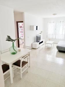 een witte woonkamer met een tafel en een bank bij Apartamento Triana in Los Silos